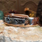 Handcrafted copper and sterling silver cuff bracelet by Navajo artisan Robert Little featuring bear paw stamped detailing in a traditional Southwestern design.  Side view.