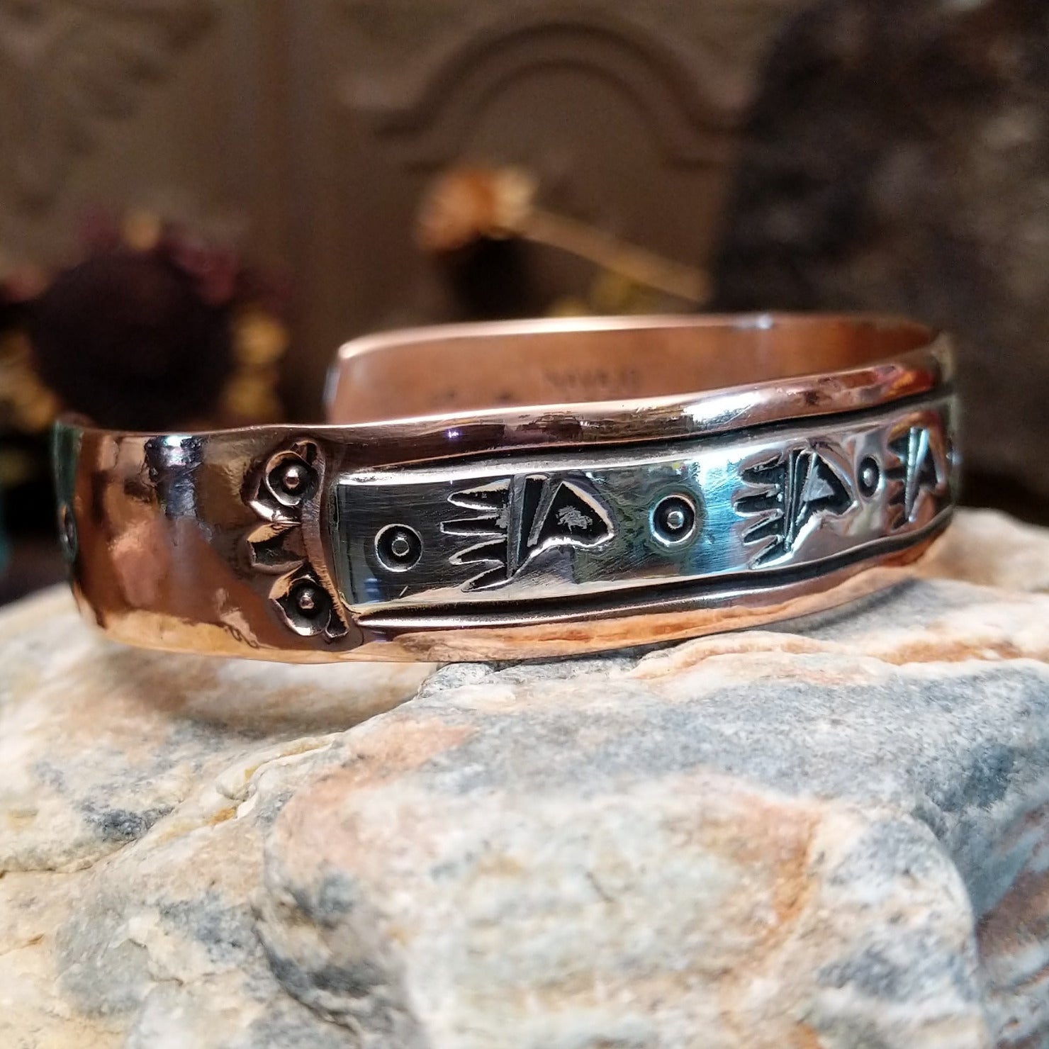 Handcrafted copper and sterling silver cuff bracelet by Navajo artisan Robert Little featuring bear paw stamped detailing in a traditional Southwestern design.  Side view.
