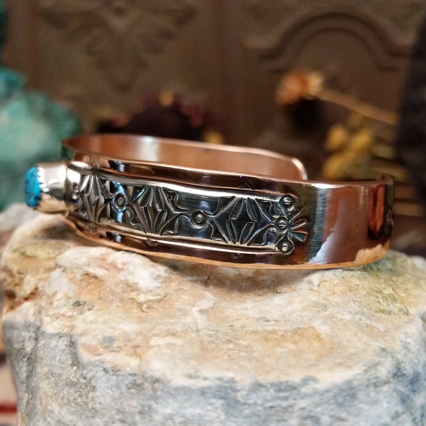 Handcrafted copper and sterling silver cuff bracelet by Navajo artisan Robert Little featuring a turquoise stone and traditional stamped detailing in a Southwestern design.  Side view.