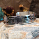 Handcrafted sterling silver cuff bracelet by Navajo artist Gilbert Begay featuring an engraved landscape storyteller design with traditional Southwestern details.  Side view.
