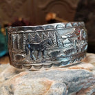 Handcrafted sterling silver cuff bracelet by Navajo artist June Delgarito featuring an engraved horse and landscape scene in a traditional Southwestern design.  Side view.