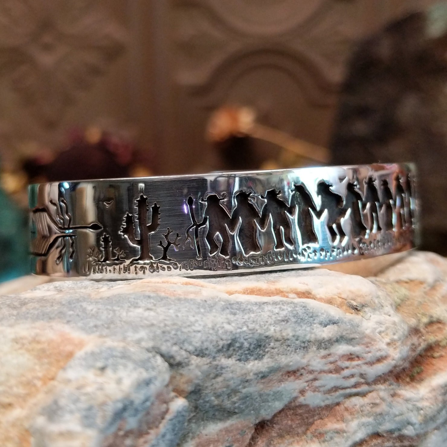 Handcrafted sterling silver cuff bracelet by Navajo artist Gilbert Begay featuring an engraved friendship dance storyteller scene in a traditional Southwestern design.  Side view.