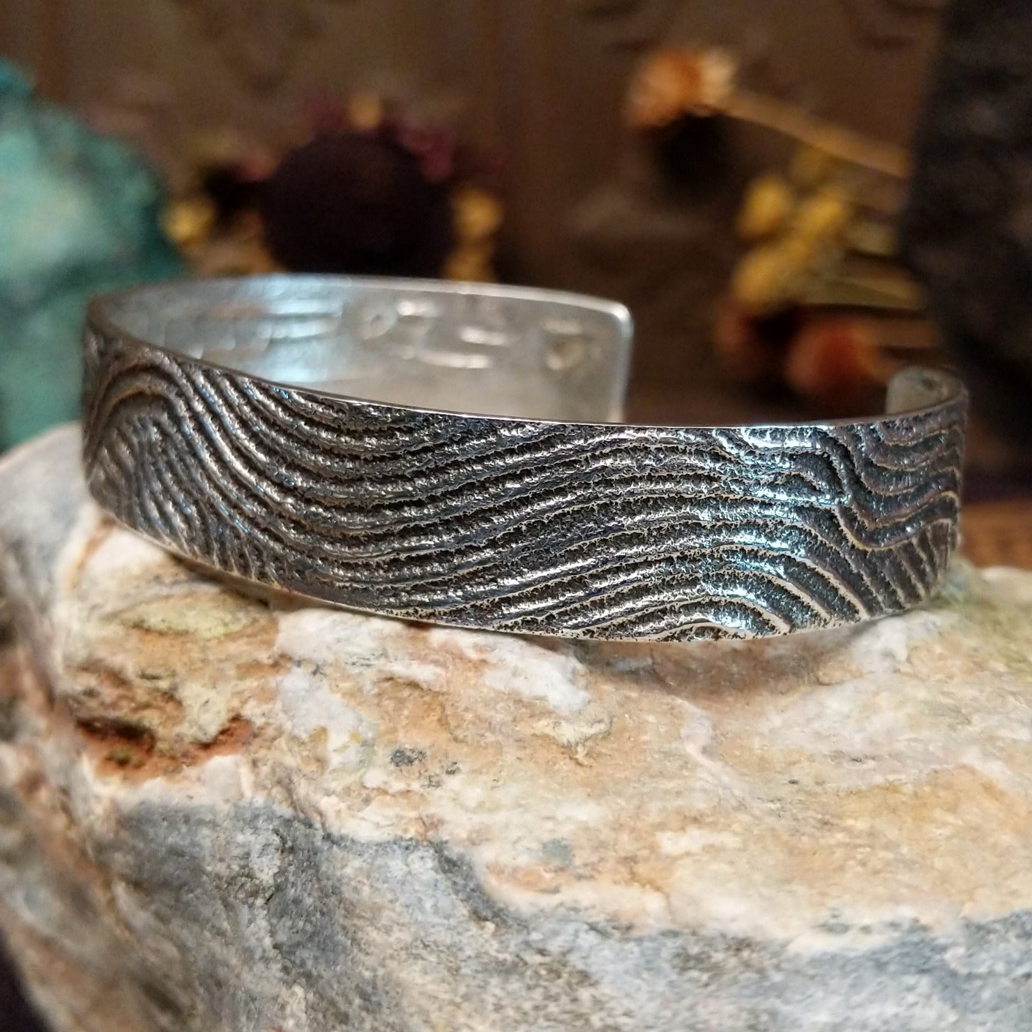 Handcrafted sterling silver cuff bracelet by Dino Garcia featuring a wavy tufa cast design with textured organic detailing in a Southwestern Native American style.  Side view.