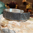 Handcrafted sterling silver cuff bracelet by Elgin Tom featuring geometric pattern detailing in a modern Southwestern Native American design.  Side view.