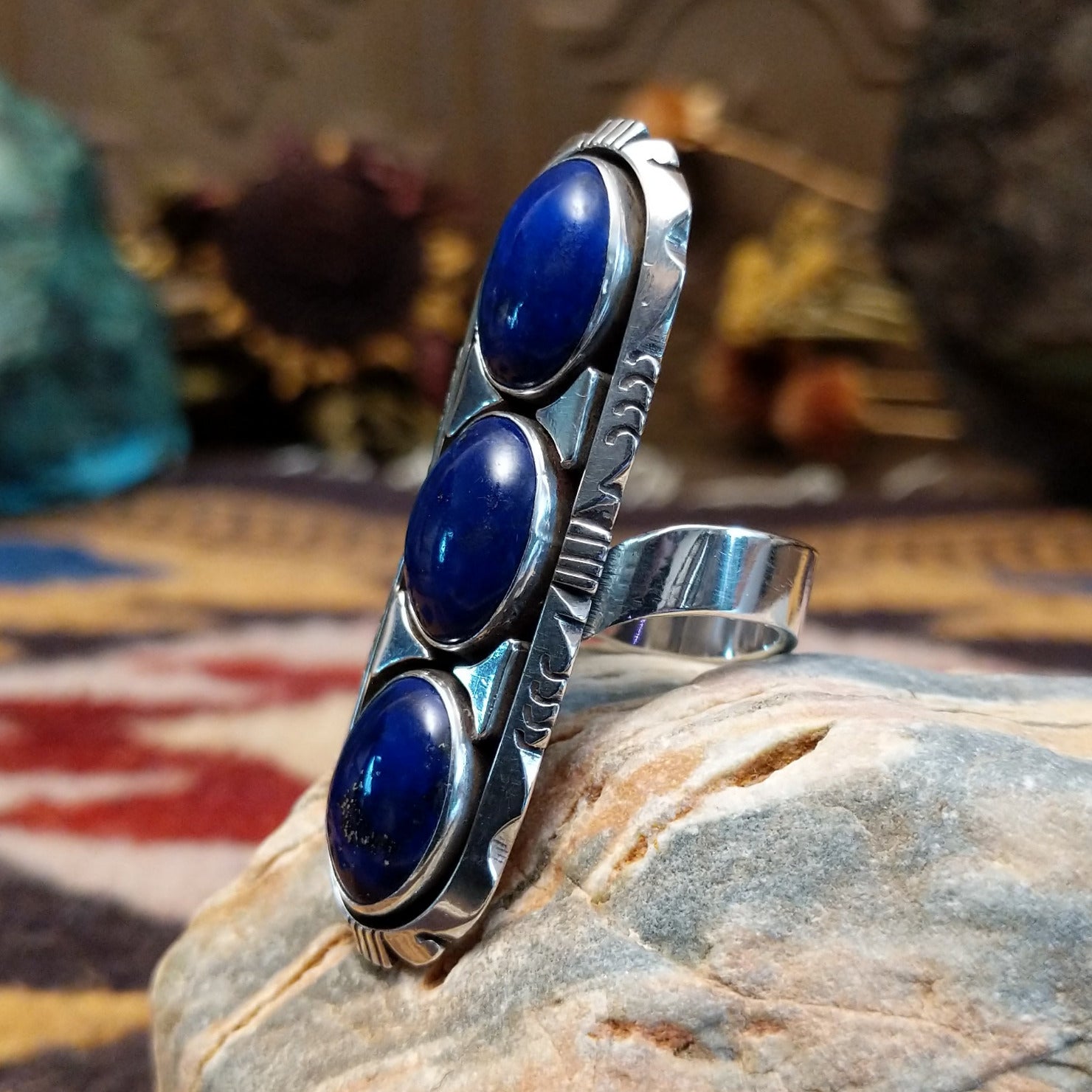 Handcrafted sterling silver ring by Toledo featuring three oval lapis stones in a vertical arrangement with geometric silver accents in a traditional Southwestern Native American design.  Side view.