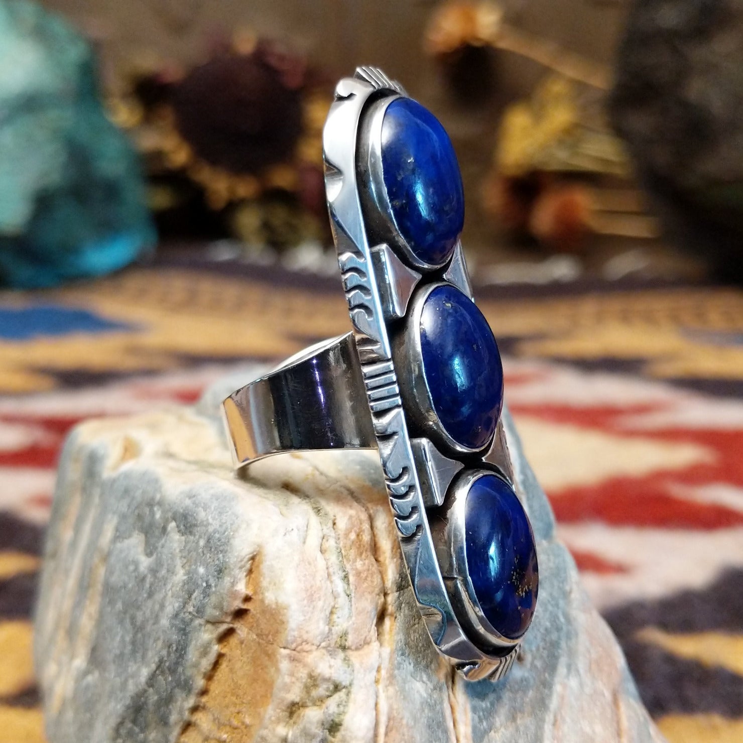 Handcrafted sterling silver ring by Toledo featuring three oval lapis stones in a vertical arrangement with geometric silver accents in a traditional Southwestern Native American design.  Side view.