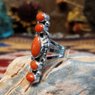 Handcrafted Navajo sterling silver ring by D.W. featuring multiple red coral stones arranged vertically with decorative silver scrollwork and traditional Southwestern detailing.  Side view.