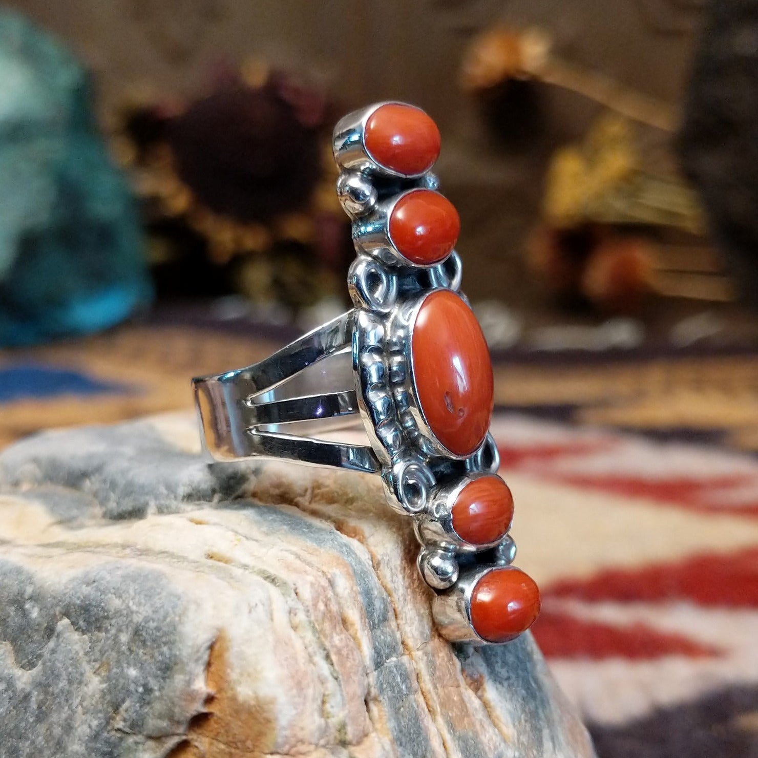 Handcrafted Navajo sterling silver ring by D.W. featuring multiple red coral stones arranged vertically with decorative silver scrollwork and traditional Southwestern detailing.  Side view.