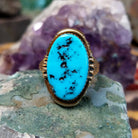 Oval turquoise ring set in a polished 14K yellow gold bezel by Delbert Gordon, featuring natural blue stone with visible matrix patterns and a smooth, minimal gold band design.