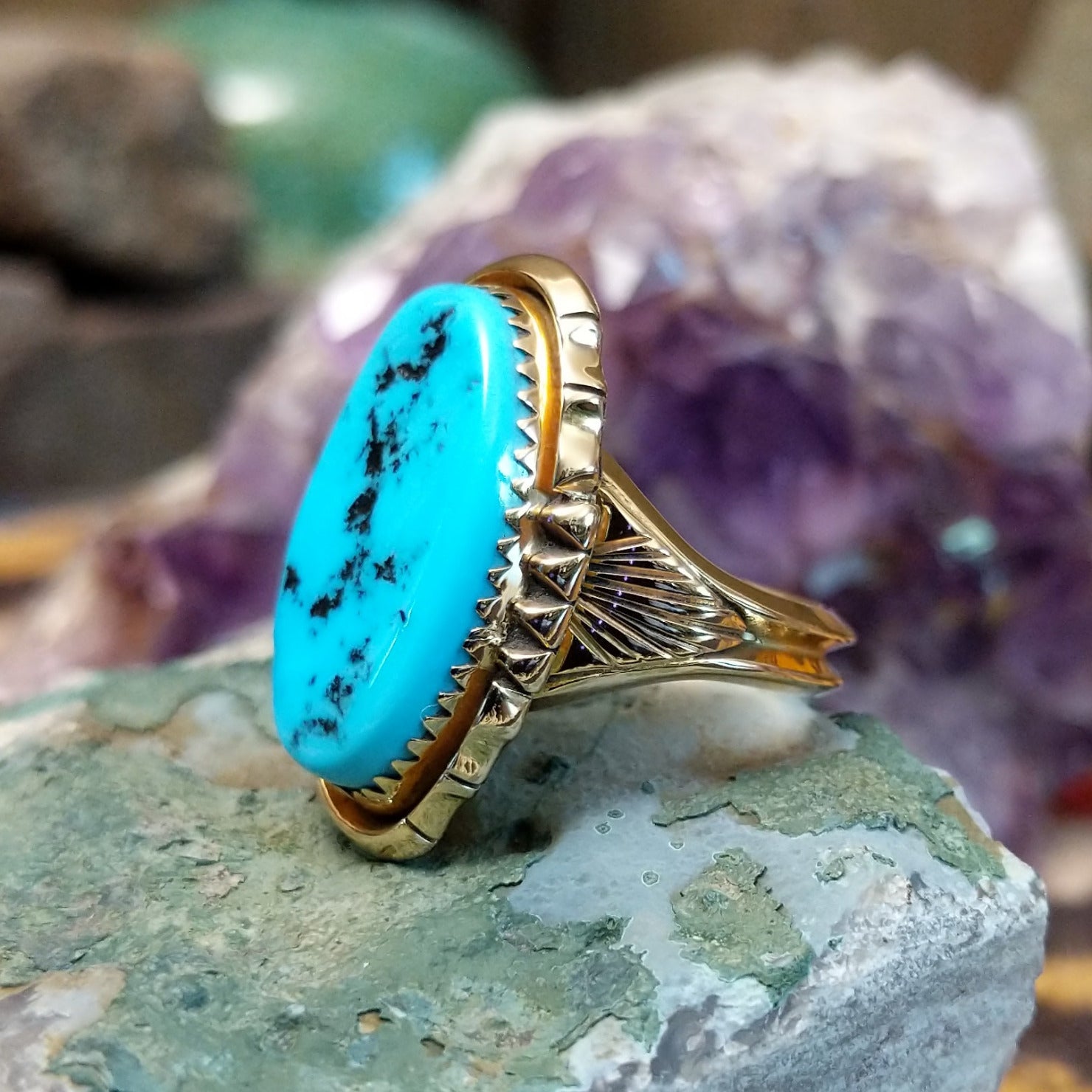 Oval turquoise ring set in a polished 14K yellow gold bezel by Delbert Gordon, featuring natural blue stone with visible matrix patterns and a smooth, minimal gold band design.  Side view.