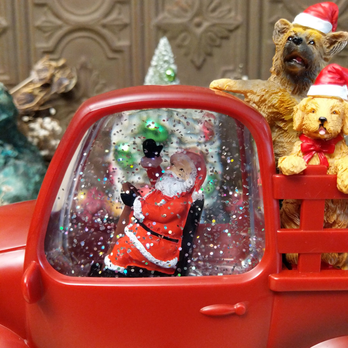 Red Christmas truck snow globe with Santa in the cab and four dogs wearing Santa hats in the truck bed.
