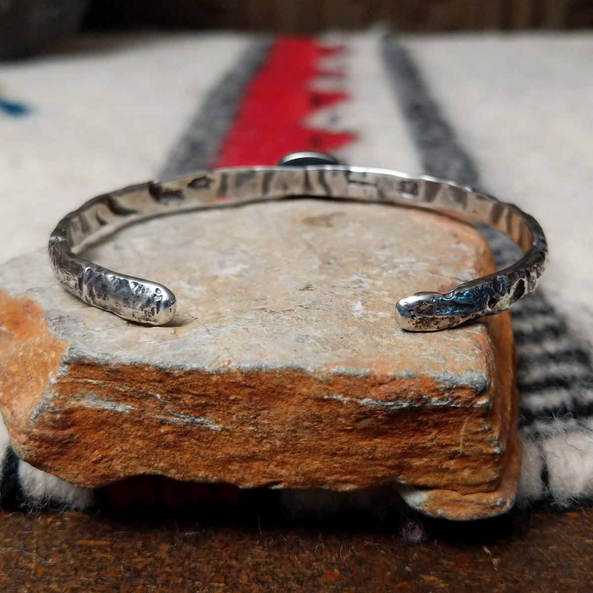 Slender silver cuff by Raymond Coriz featuring a pale green oval Palomino variscite stone centered on a textured, oxidized silver band; underside view.