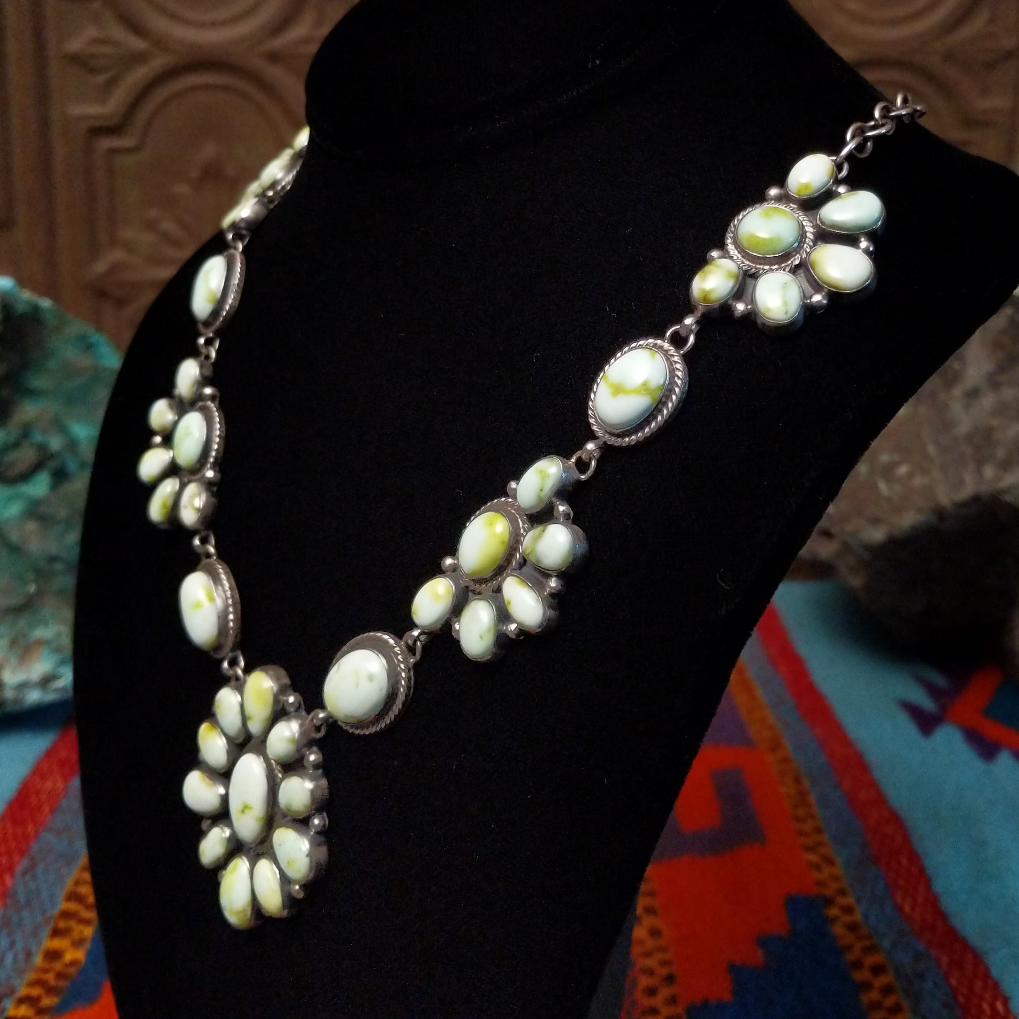 Palomino Variscite Sterling Silver necklace  by Geraldine James, featuring white, cream, pale green, and yellow-green stones arranged in floral-style clusters; side view.