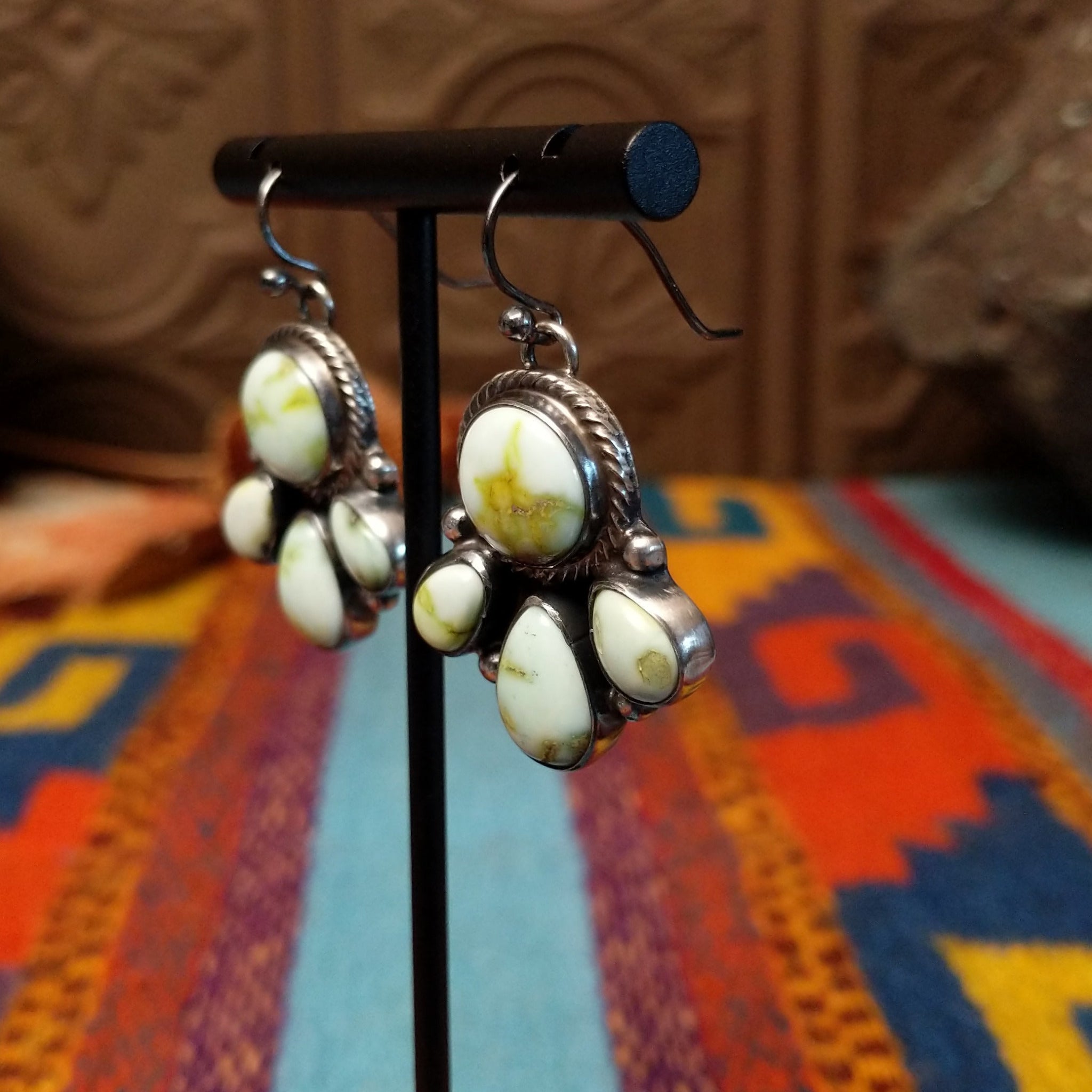 Palomino Variscite Sterling Silver earrings by Geraldine James, featuring white, cream, pale green, and yellow-green stones arranged in floral-style clusters; side view.