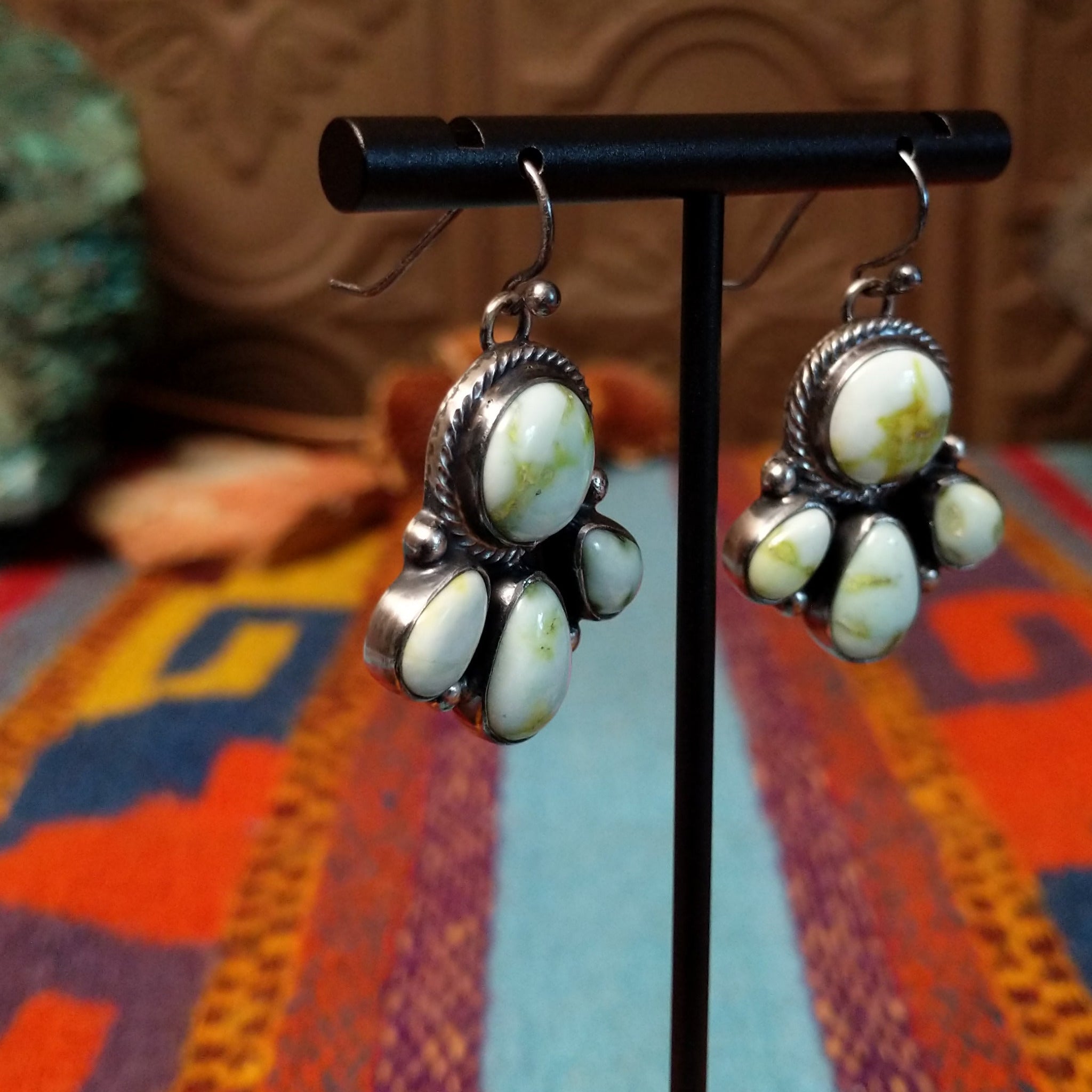 Palomino Variscite Sterling Silver earrings by Geraldine James, featuring white, cream, pale green, and yellow-green stones arranged in floral-style clusters; side view.