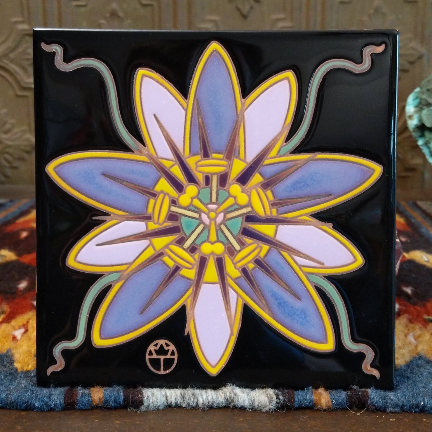Ceramic tile showcasing a passion flower with purple and yellow petals on a glossy black background.