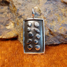 Patinaed sterling silver pendant set in a relief.