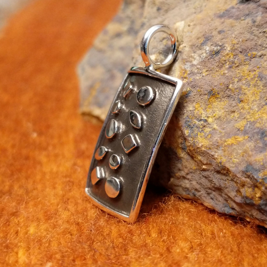 Patinaed sterling silver pendant set in a relief.