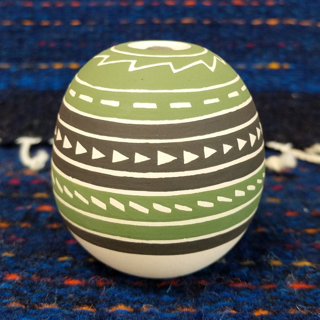 Geometric motifs on the green, brown, and white clay of the pottery piece.