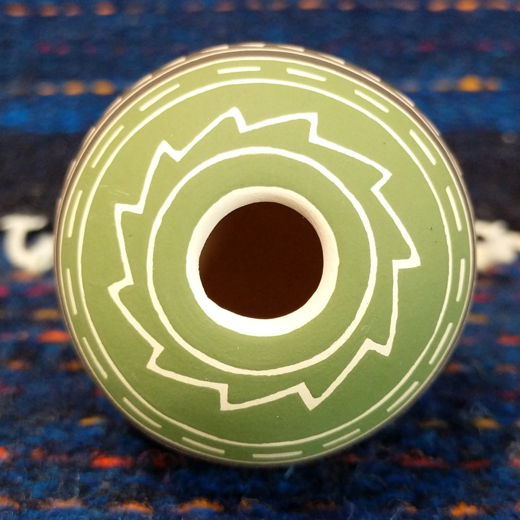 The narrow opening of the pottery piece with geometric designs surrounding its' edge.