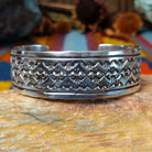 Wide silver cuff by Freddie Maloney with repeating rows of geometric stamped patterns and smooth borders.