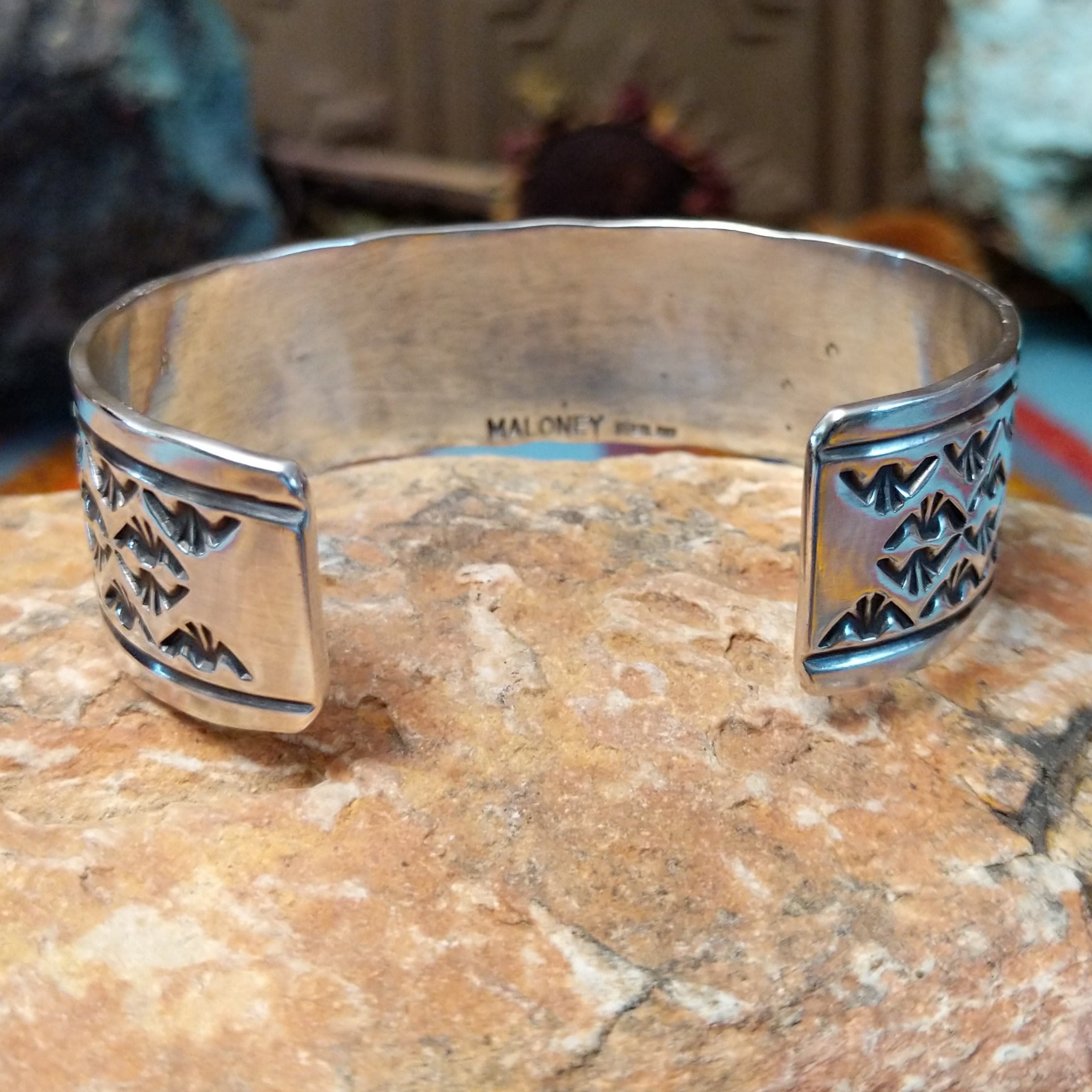 Wide silver cuff by Freddie Maloney with repeating rows of geometric stamped patterns and smooth borders.
