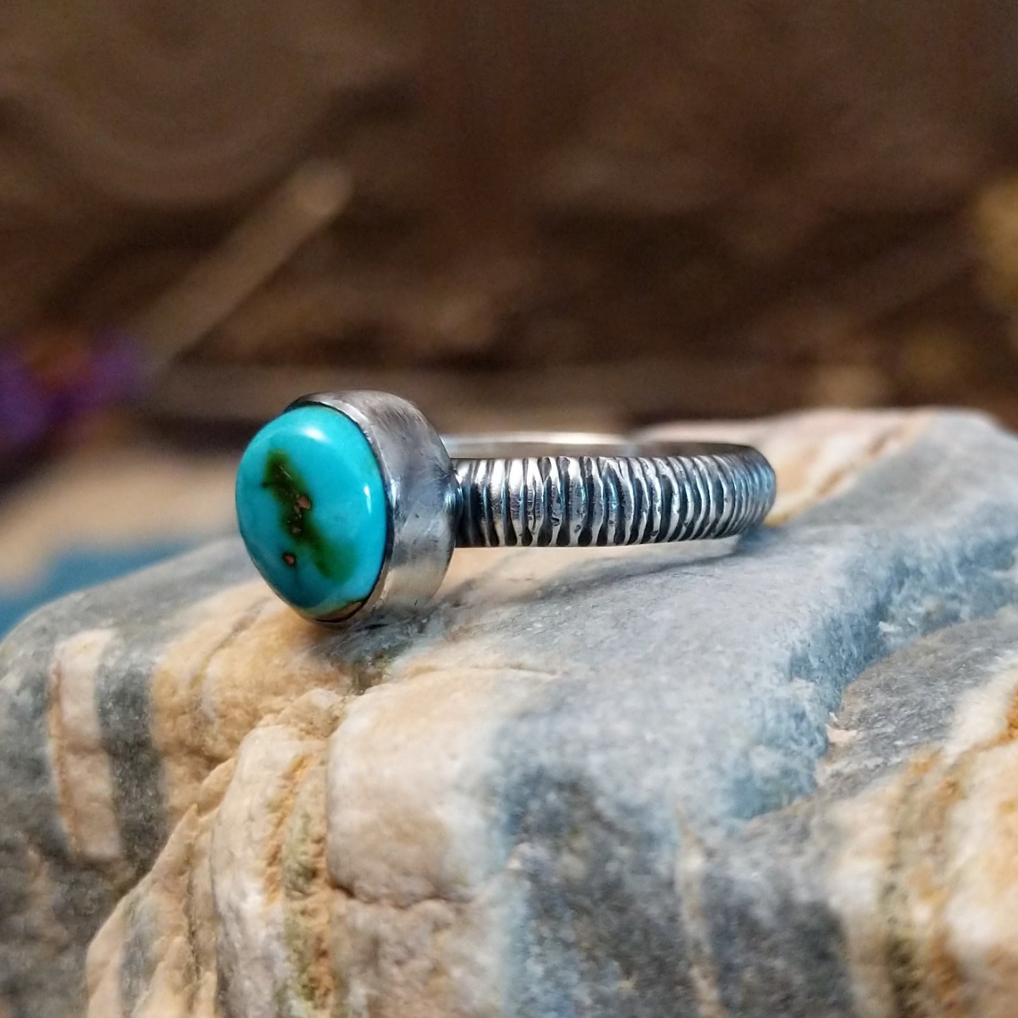 Sterling silver ring with turquoise set in the oval bezel and ribbed band.