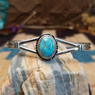 Sterling silver cuff with turquoise set in a round bezel, framed by twisted rope and an incised setting.