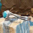 Sterling silver cuff with turquoise set in a round bezel, framed by twisted rope and an incised setting.