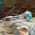Sterling silver cuff with turquoise set in a round bezel, framed by twisted rope and an incised setting.