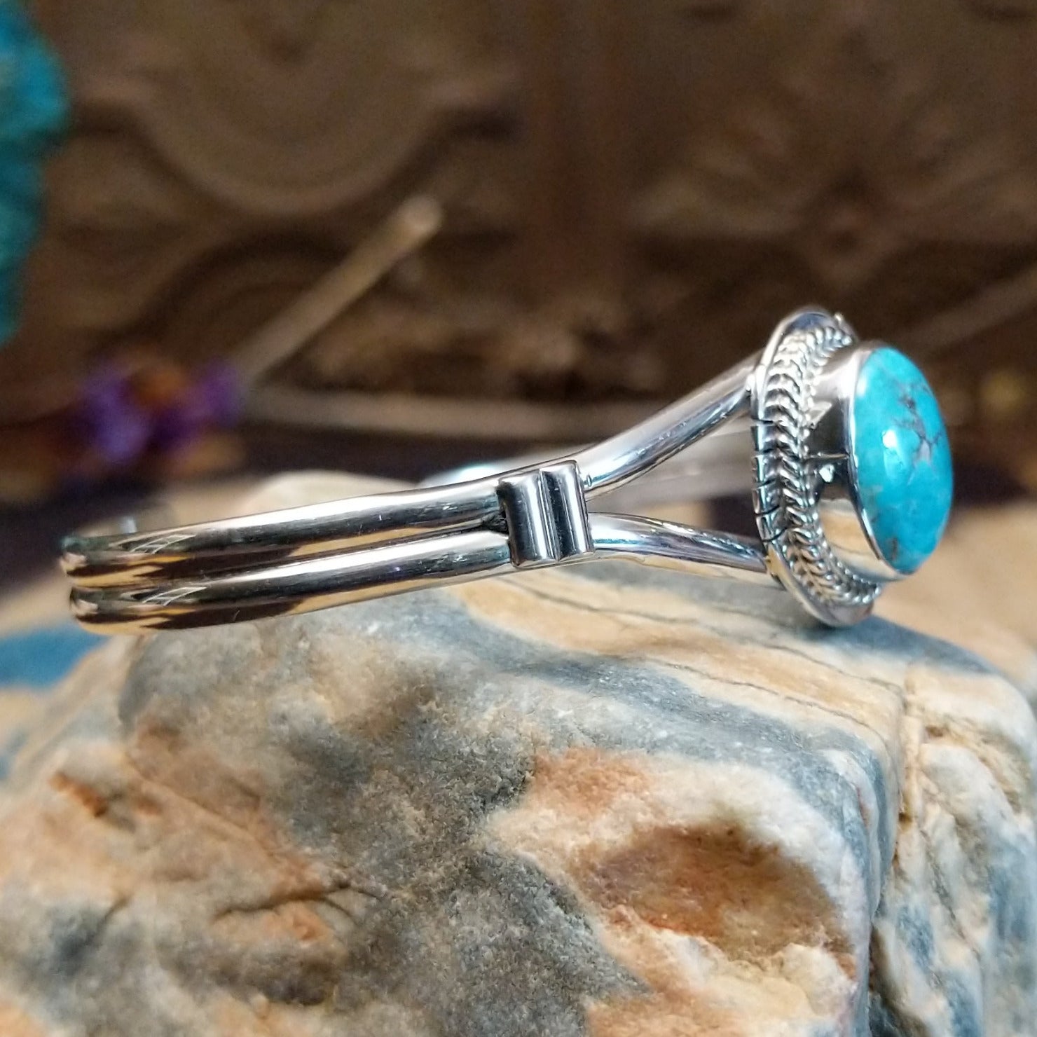 Sterling silver cuff with turquoise set in a round bezel, framed by twisted rope and an incised setting.