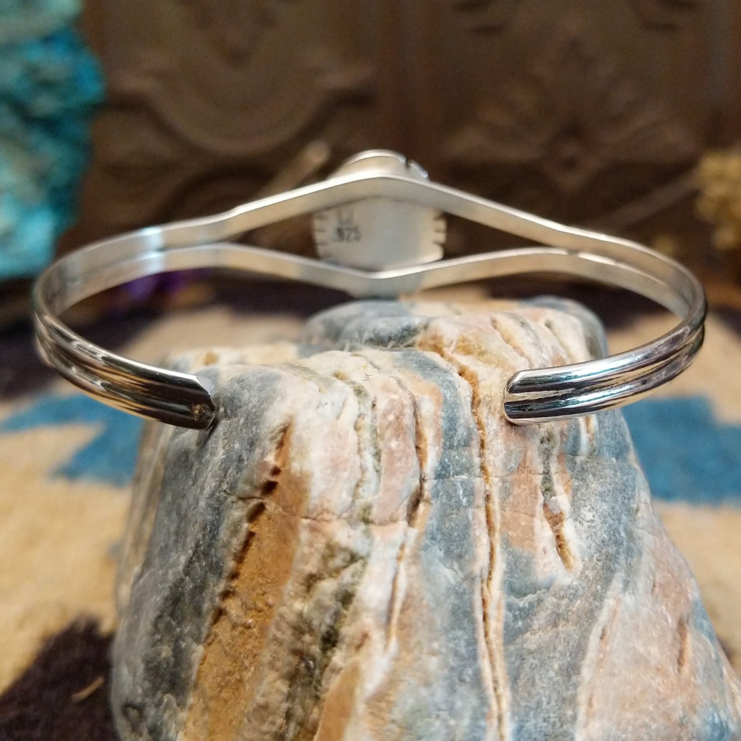 Sterling silver cuff with turquoise set in a round bezel, framed by twisted rope and an incised setting.