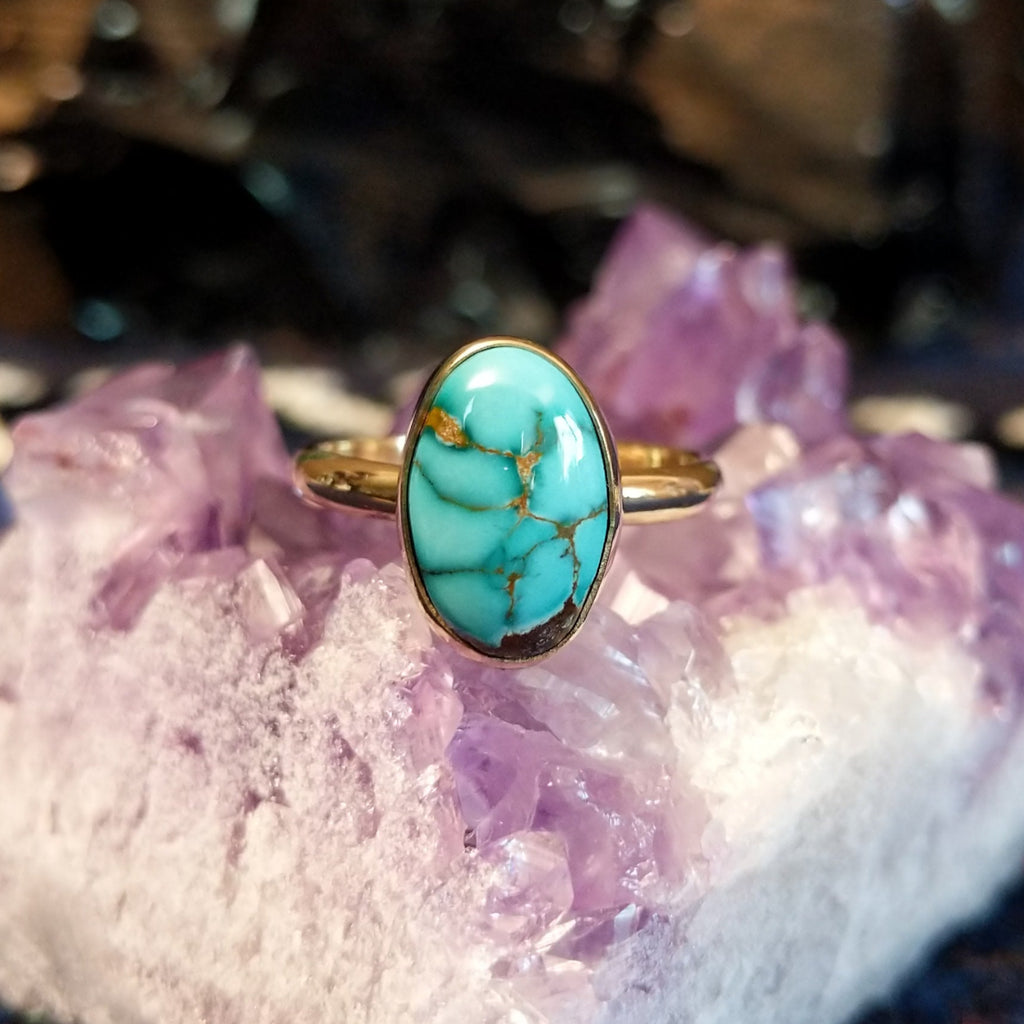Gold ring featuring an oval Pilot Mountain turquoise stone with visible brown matrix.