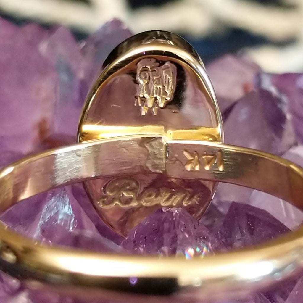 The artist's signature is etched onto the bezel of the ring.