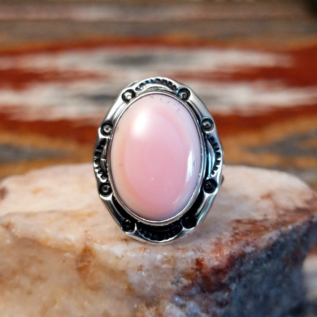 Sterling silver ring with layered band and rhodochrosite framed by ornate bezel.