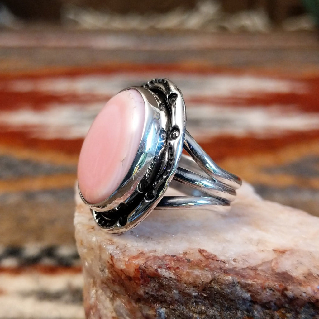 Sterling silver ring with layered band and rhodochrosite framed by ornate bezel.
