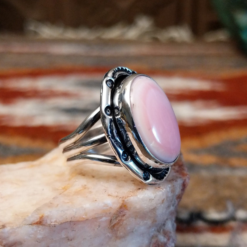 Sterling silver ring with layered band and rhodochrosite framed by ornate bezel.