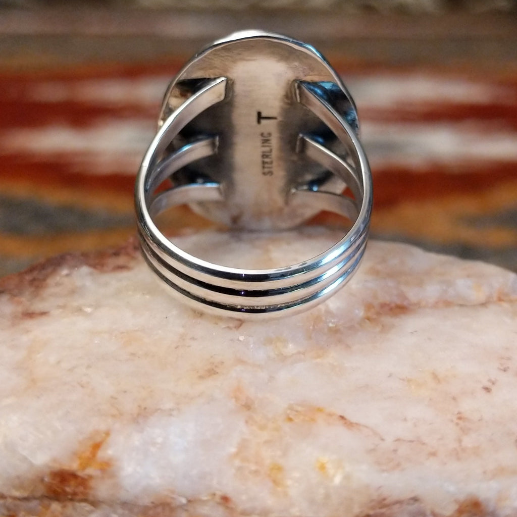 Sterling silver ring with layered band and rhodochrosite framed by ornate bezel.