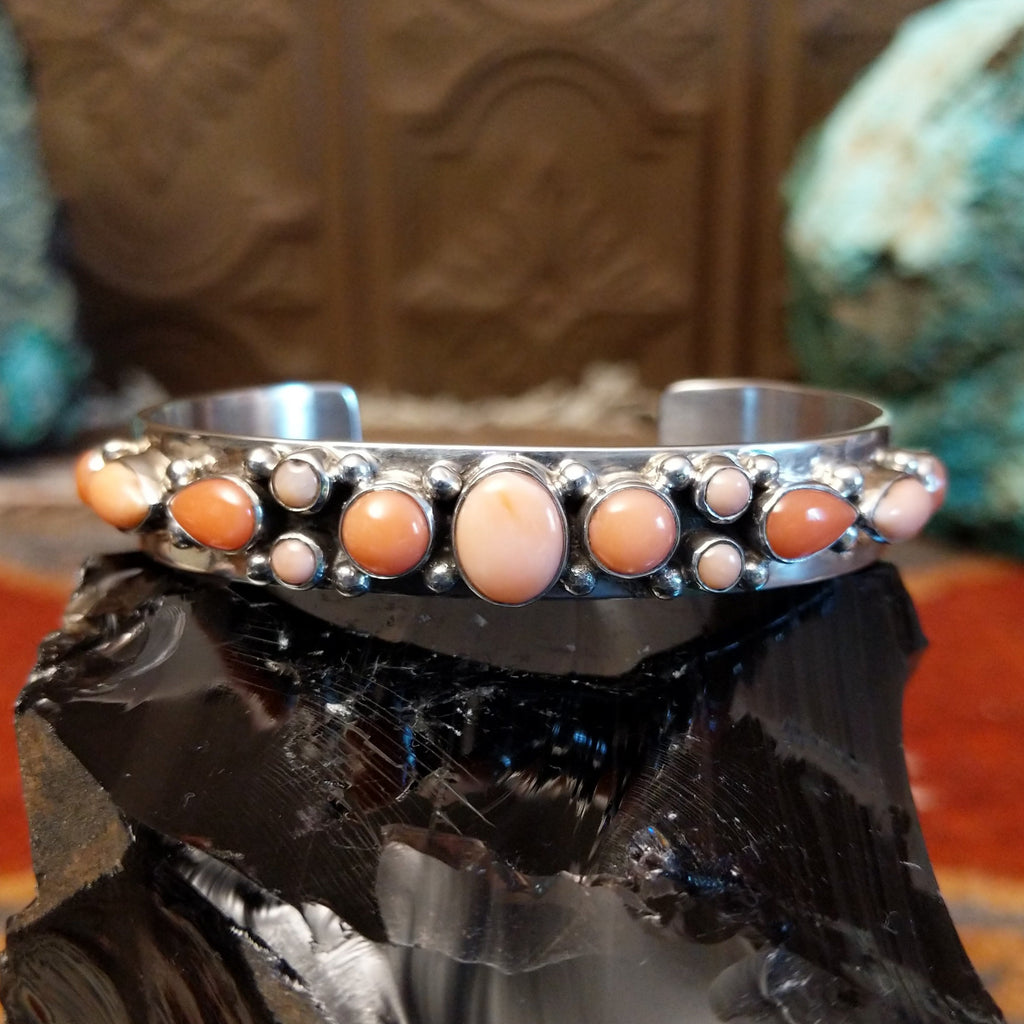 Sterling silver cuff bracelet with sporadic arrangement of pink coral set in the bezels.