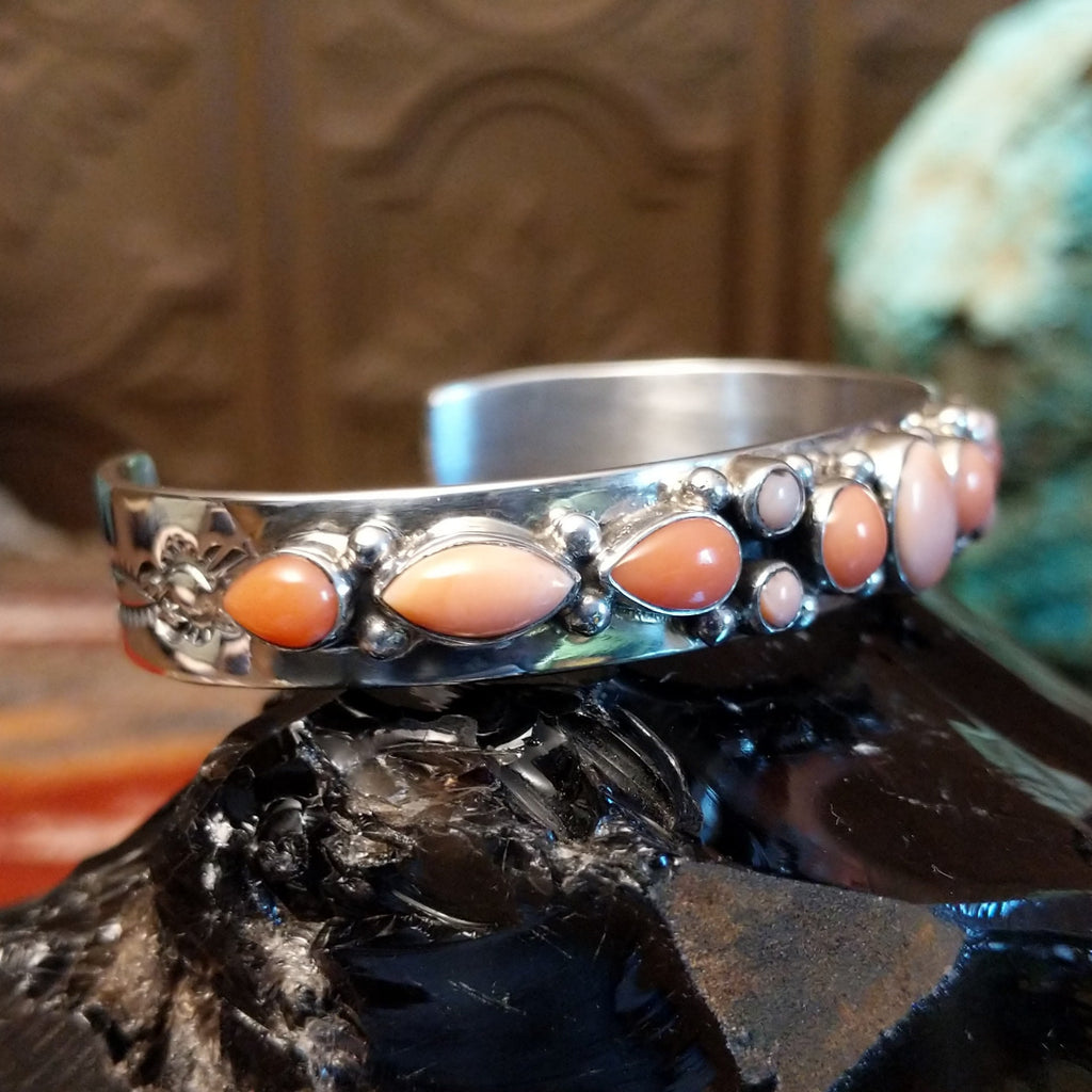 Sterling silver cuff bracelet with sporadic arrangement of pink coral set in the bezels.