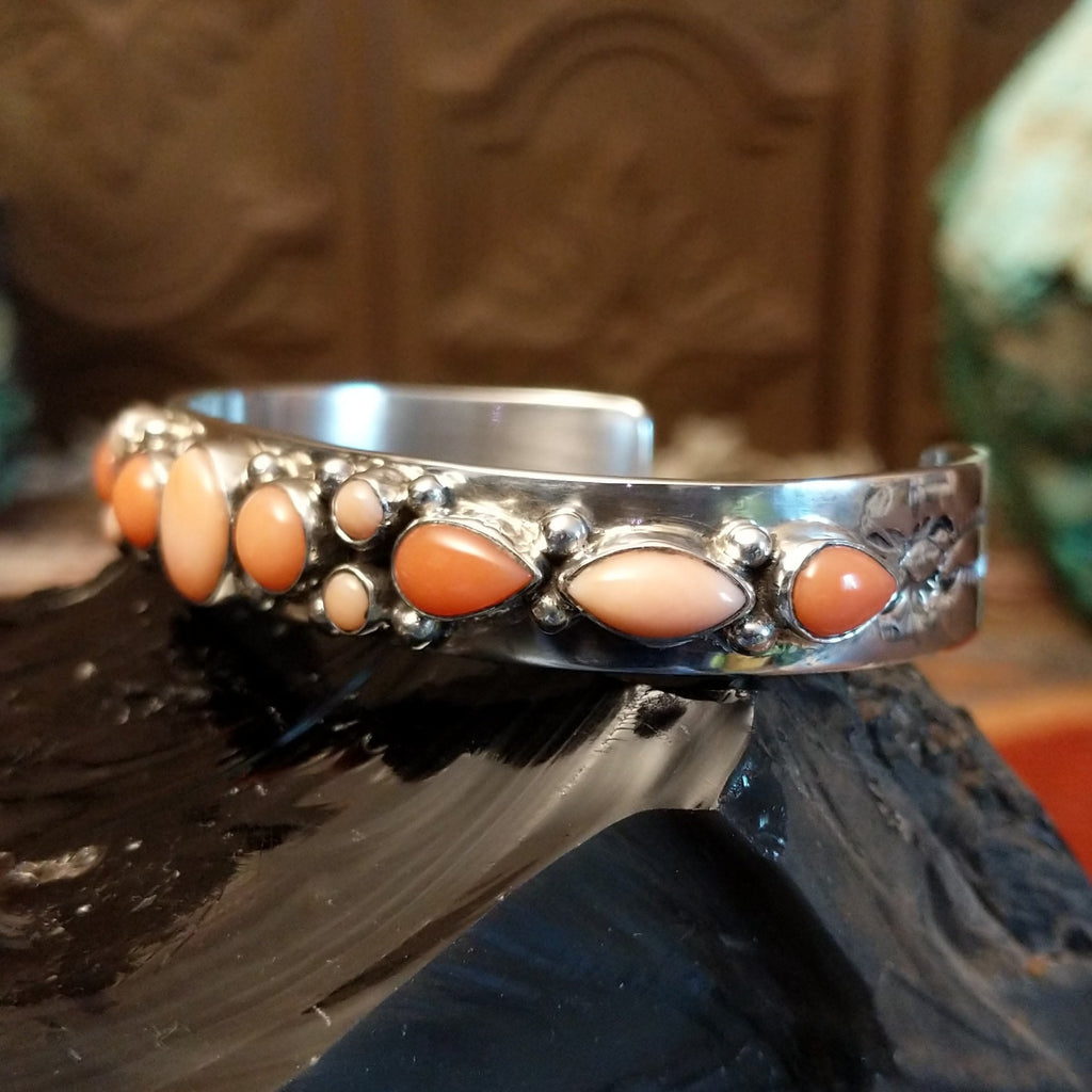 Sterling silver cuff bracelet with sporadic arrangement of pink coral set in the bezels.