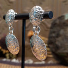 Sterling silver planished circle earrings featuring textured round dangles and matching textured stud tops.