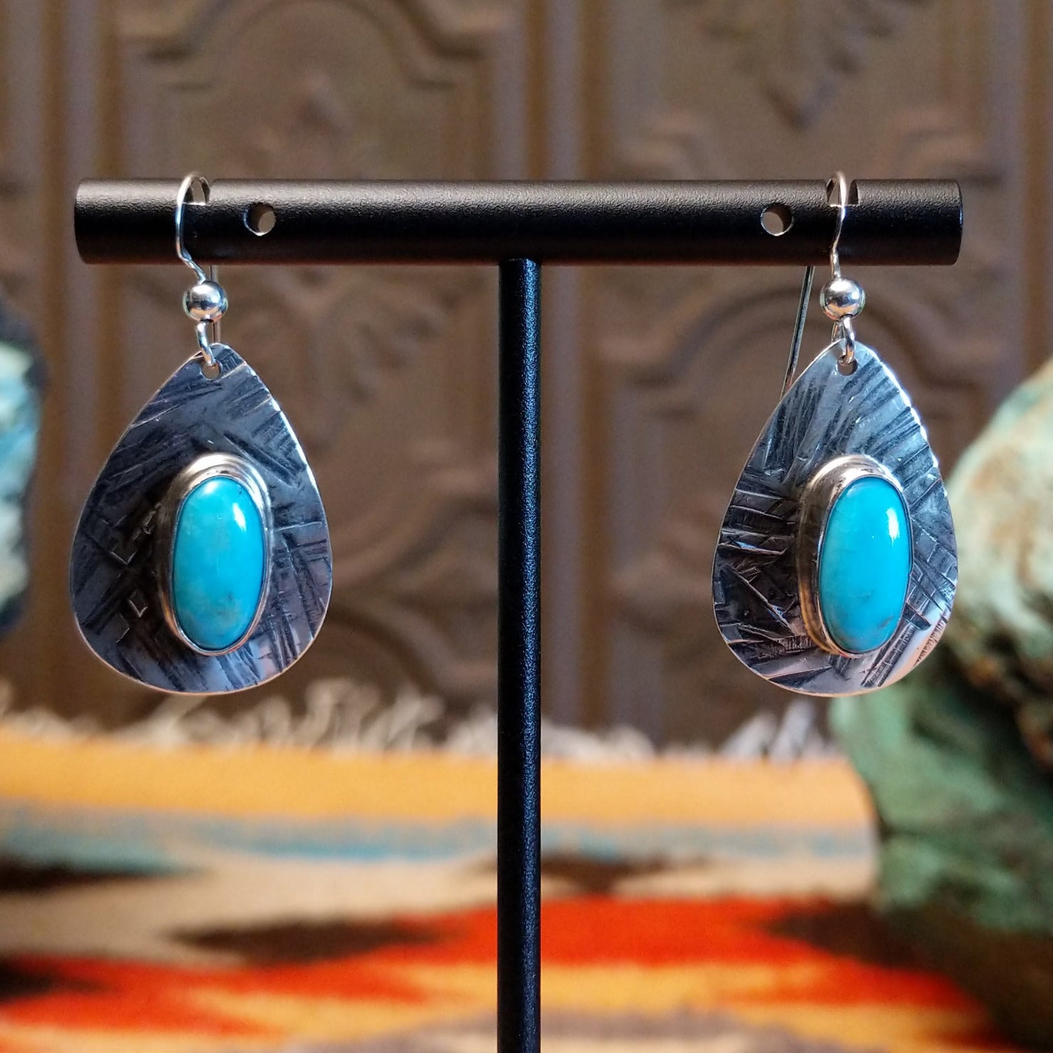 Sterling silver earrings with turquoise set in the oval bezels that are framed by the planished settings.