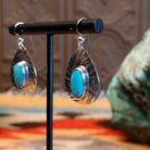 Sterling silver earrings with turquoise set in the oval bezels that are framed by the planished settings.