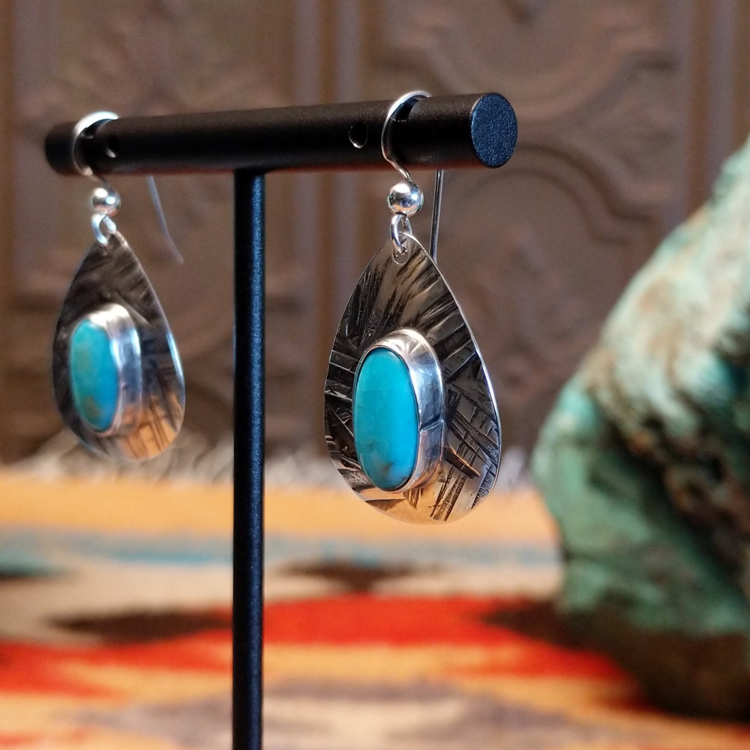 Sterling silver earrings with turquoise set in the oval bezels that are framed by the planished settings.