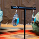 Sterling silver earrings with turquoise set in the oval bezels that are framed by the planished settings.