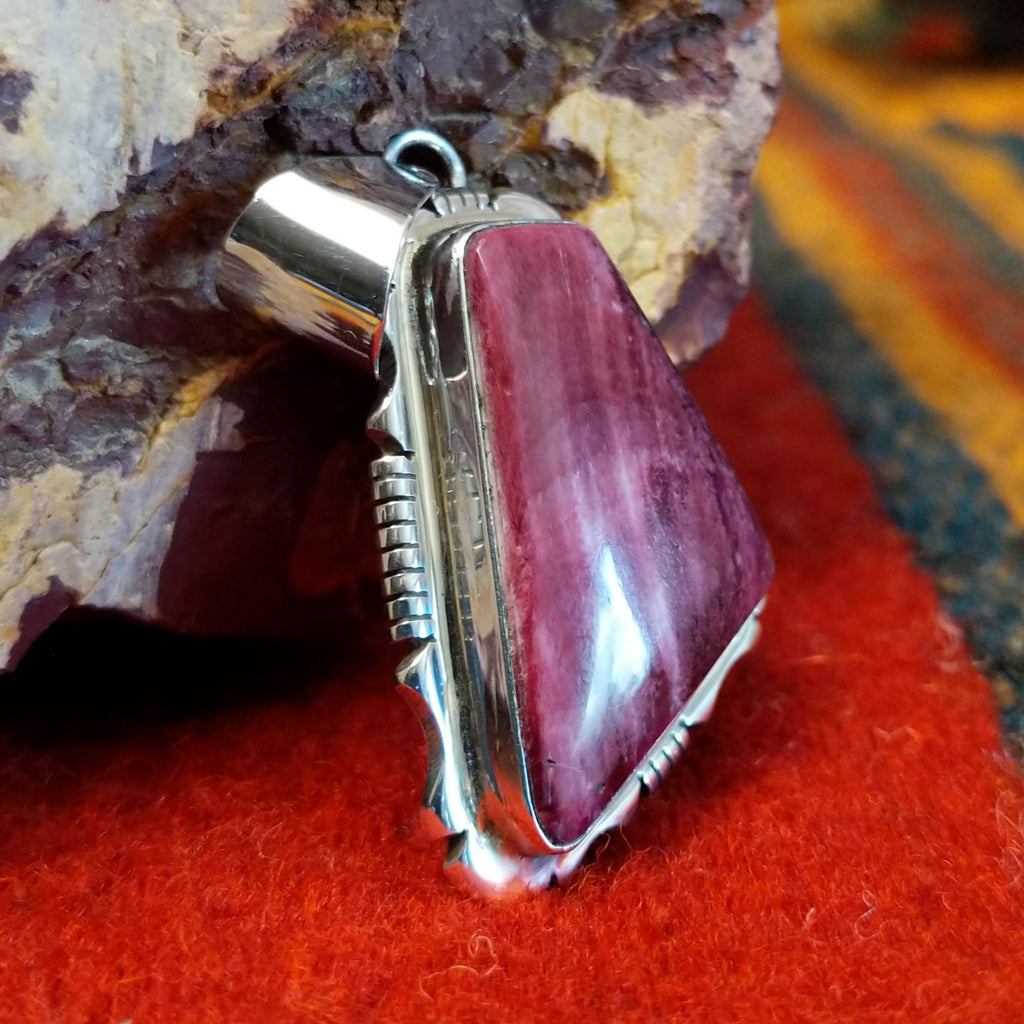 Quadrilateral purple spiny oyster shell set in sterling silver with intricately incised frame.