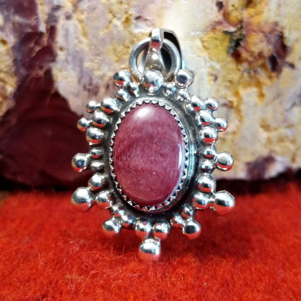 Oval purple spiny oyster shell set in a notched sterling silver bezel and intricately dotted in an outward design.