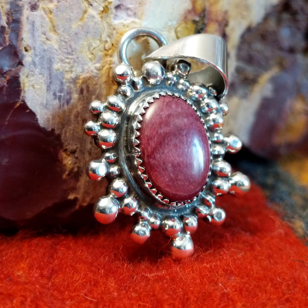 Oval purple spiny oyster shell set in a notched sterling silver bezel and intricately dotted in an outward design.