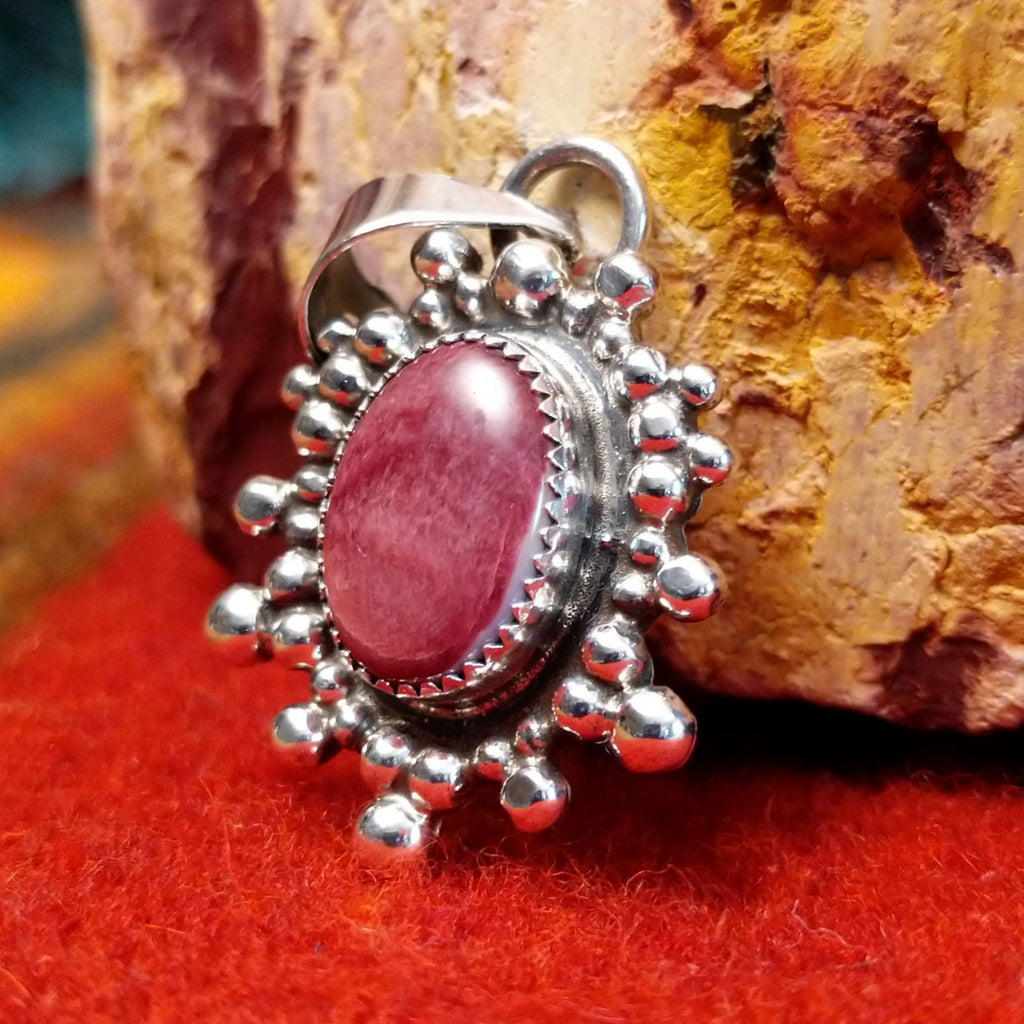 Oval purple spiny oyster shell set in a notched sterling silver bezel and intricately dotted in an outward design.